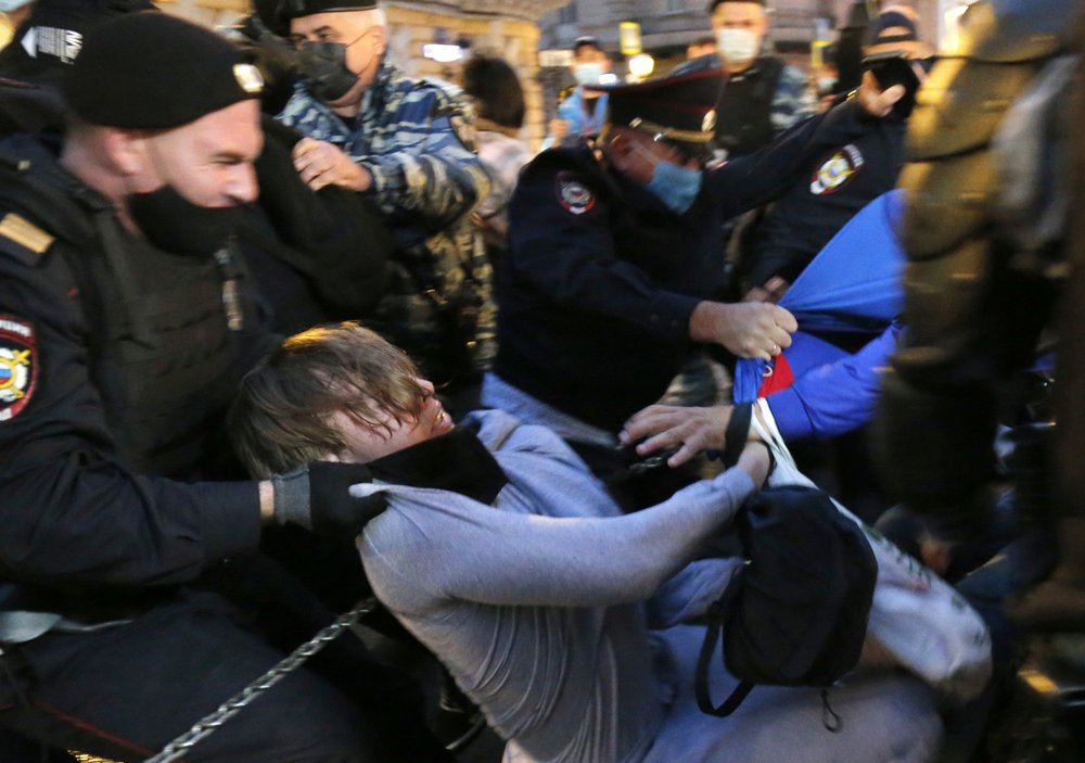 Police officers detain a protester 