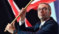 leader Herbert Kickl holds a large Austrian flag while speaking at a political rally.