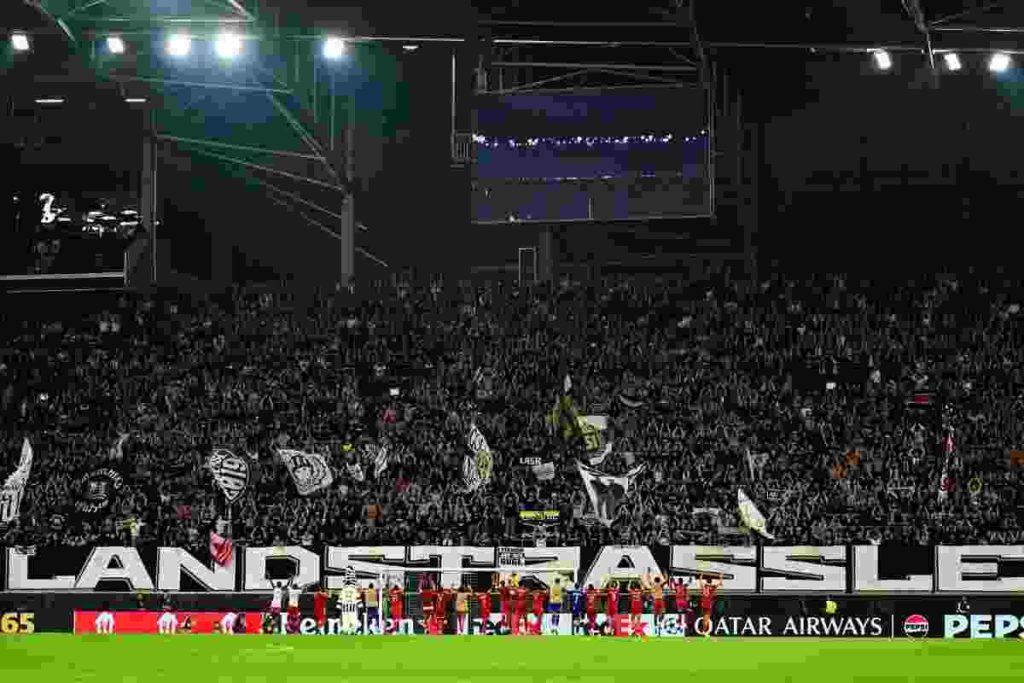 LASK players celebrating on the pitch with fans after securing a dramatic Champions League playoff victory over Celtic at Raiffeisen Arena.