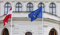 Austrian Parliament building in Vienna with European Union and Austrian flags waving.