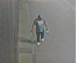 Surveillance camera footage showing the suspect walking along a sidewalk wearing a t-shirt, dark trousers, and white shoes