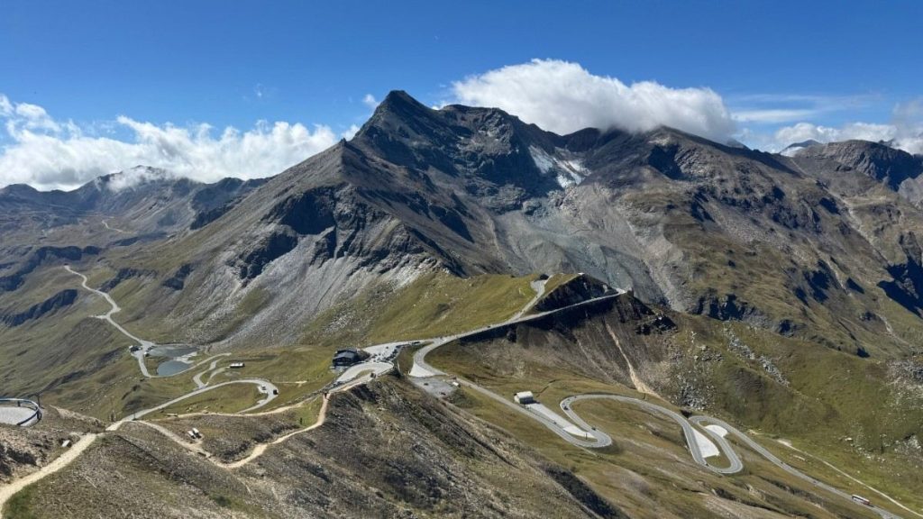 Aerial panoramic view of the winding Grossglockner High Alpine Road serpentine curves passing Fuscher Törl surrounded by mountain peaks in the Hohe Tauern range.