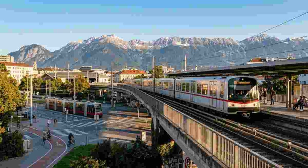 Scenic colorful houses in Innsbruck set against alpine mountains representing regional Austrian cities.