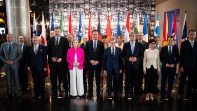 Foreign ministers and delegates from Western Balkan states and European Union members posing for a group photo in front of national flags at the Berlin Process summit in Montenegro