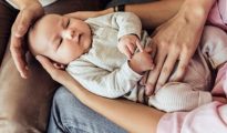 Parents gently cradling a newborn infant in their lap.